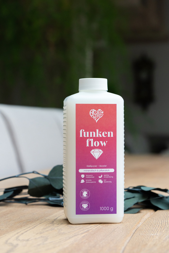 Nahaufnahme einer Flasche Funkenflow Gießpulver-Booster auf einem Holztisch in wohnlicher Atmosphäre.